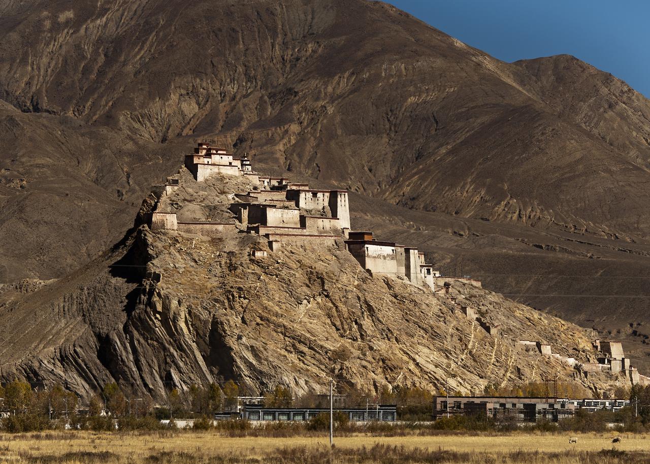 江孜宗山古堡远景，白色和红色交错的城堡从灰褐色岩石山脊上拔起