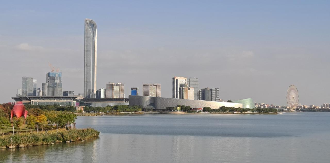 从金鸡湖西岸看苏州工业园区天际线，高层商务建筑与绿地交错