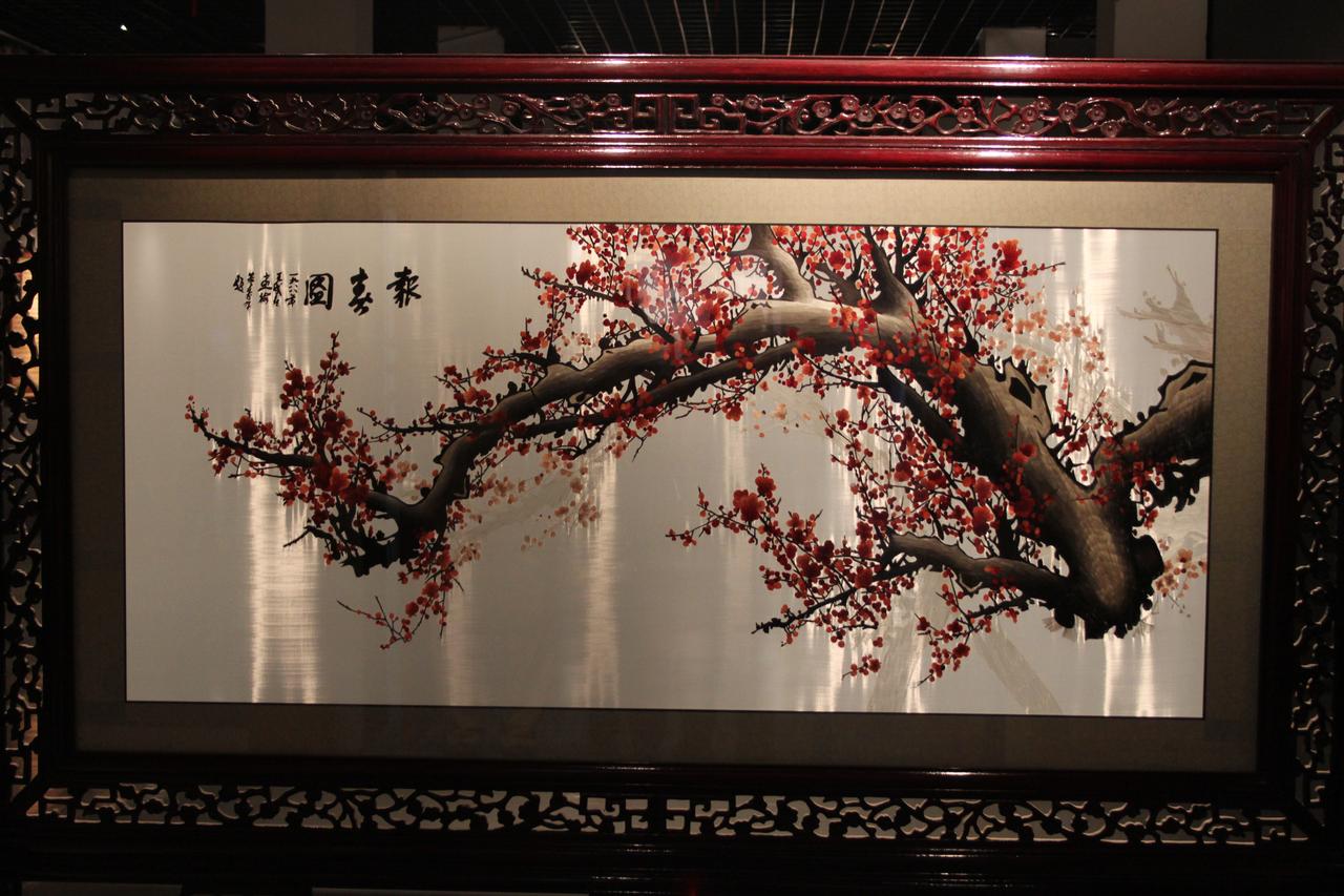 博物馆展柜中陈列的苏绣作品，装裱后作为独立艺术品展示