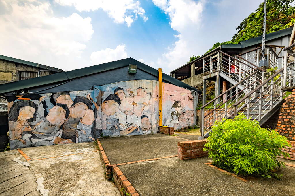 A colorful mural depicting a group of people is painted on a wall at the Taipei 