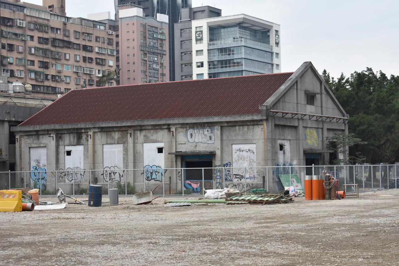 南港瓶盖工厂厂房群外观，低矮红砖厂房与后方高层新建大楼形成强烈对比