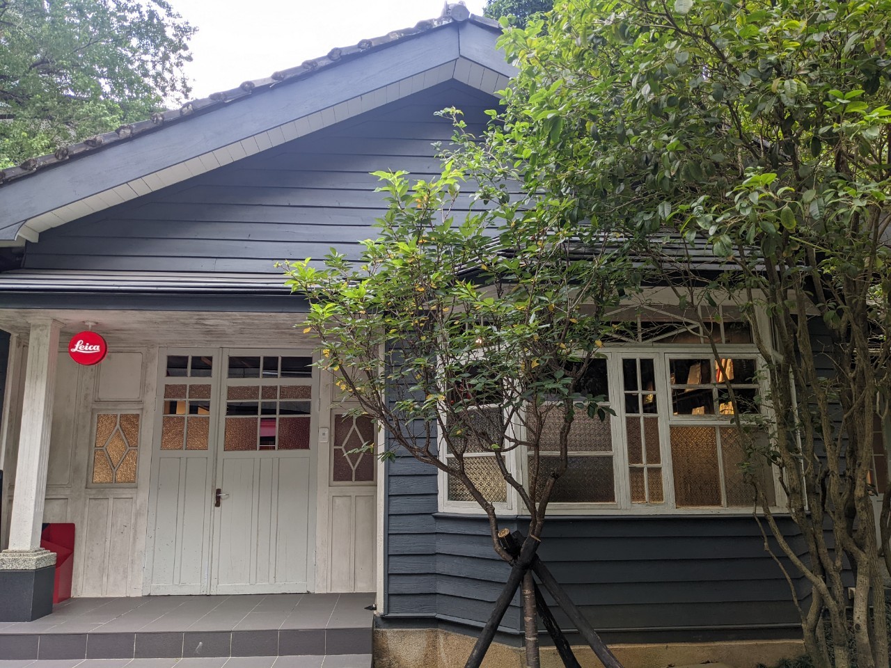 A blue wooden Japanese-style dormitory with a gabled roof, decorated with a Leic