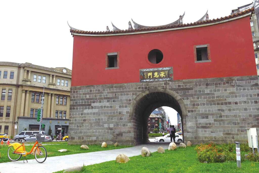 A traditional red-brick gate with an arched entrance and circular window sits at