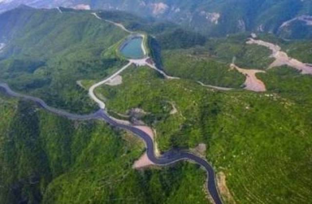 西山国家矿山公园的生态修复区，蜿蜒的道路和池塘点缀在重新变绿的山丘之间。