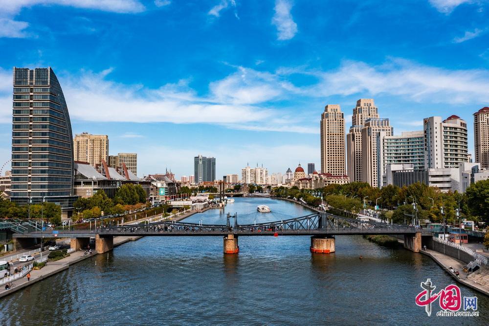 金汤桥全景，深色钢桁架结构跨过海河，远处是欧式建筑和钟楼