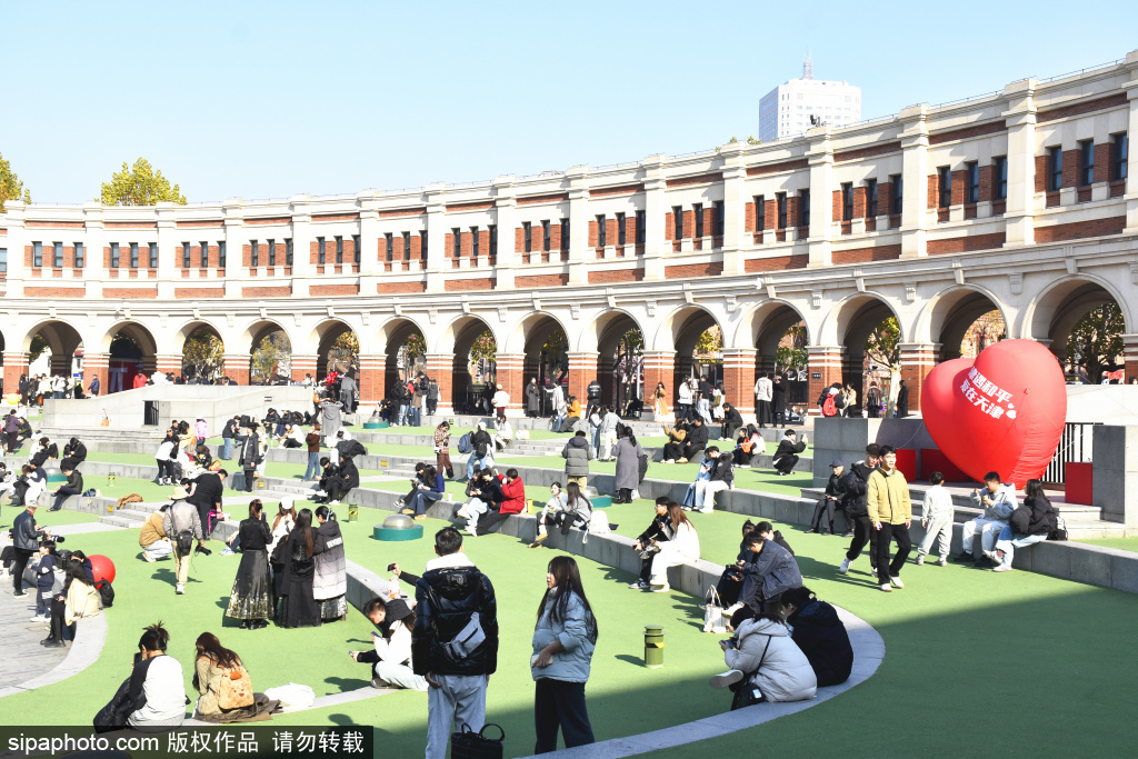 民园广场下沉草坪与拱廊全景，看台轮廓保留1920年代尺度，拱廊下方已变为商铺