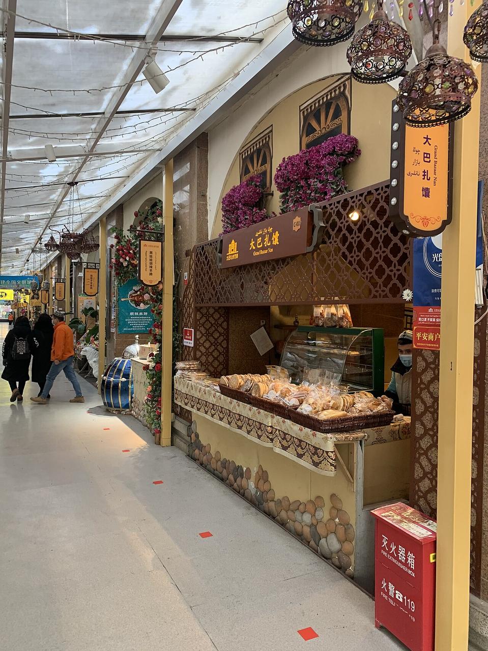 二道桥市场的食品摊位，馕和糕点直接摆在柜台上，体现了市场与日常饮食的不分界