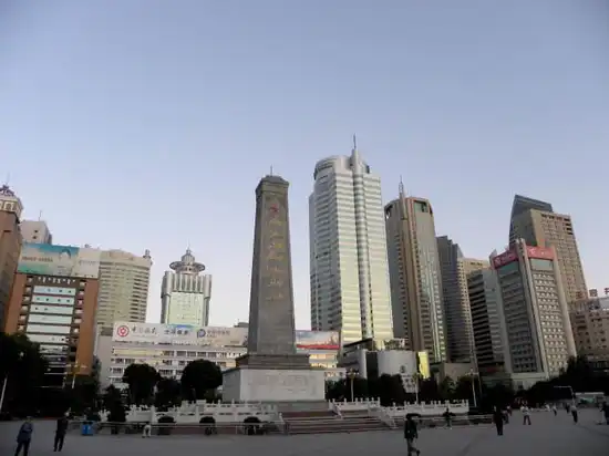 乌鲁木齐人民广场全景，纪念碑矗立在广场中轴线上，远处是自治区政府大楼