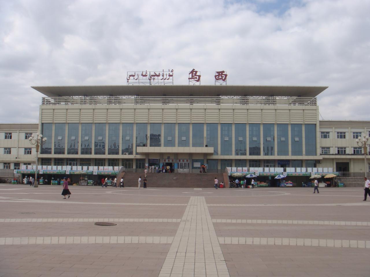 乌鲁木齐站站房远观，大型现代化建筑，前方有行人和开阔广场