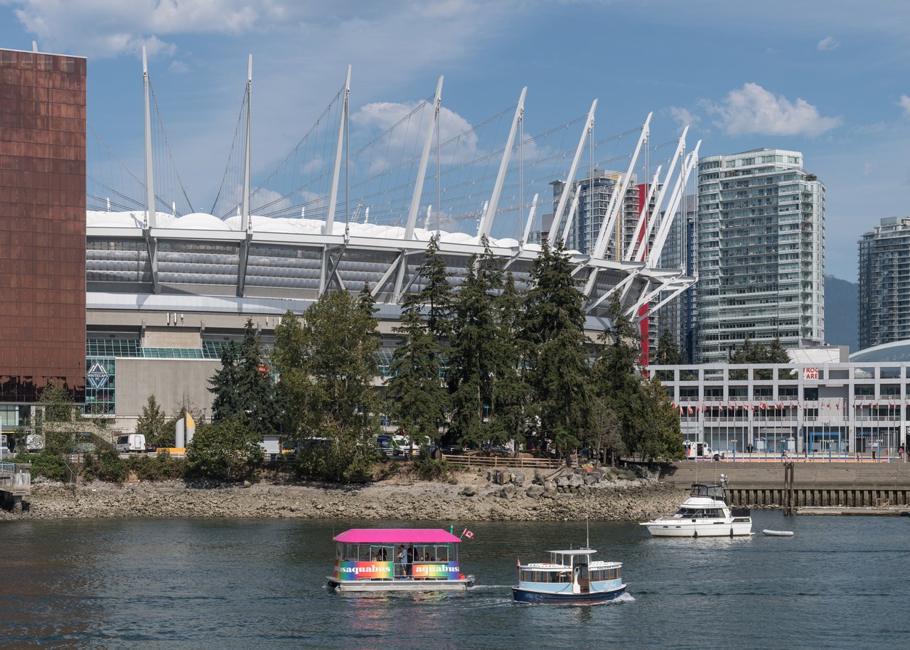 BC Place 南侧现状，36 根白色钢桅杆、拉索和织物屋顶，从 Terry Fox Plaza 方向可见