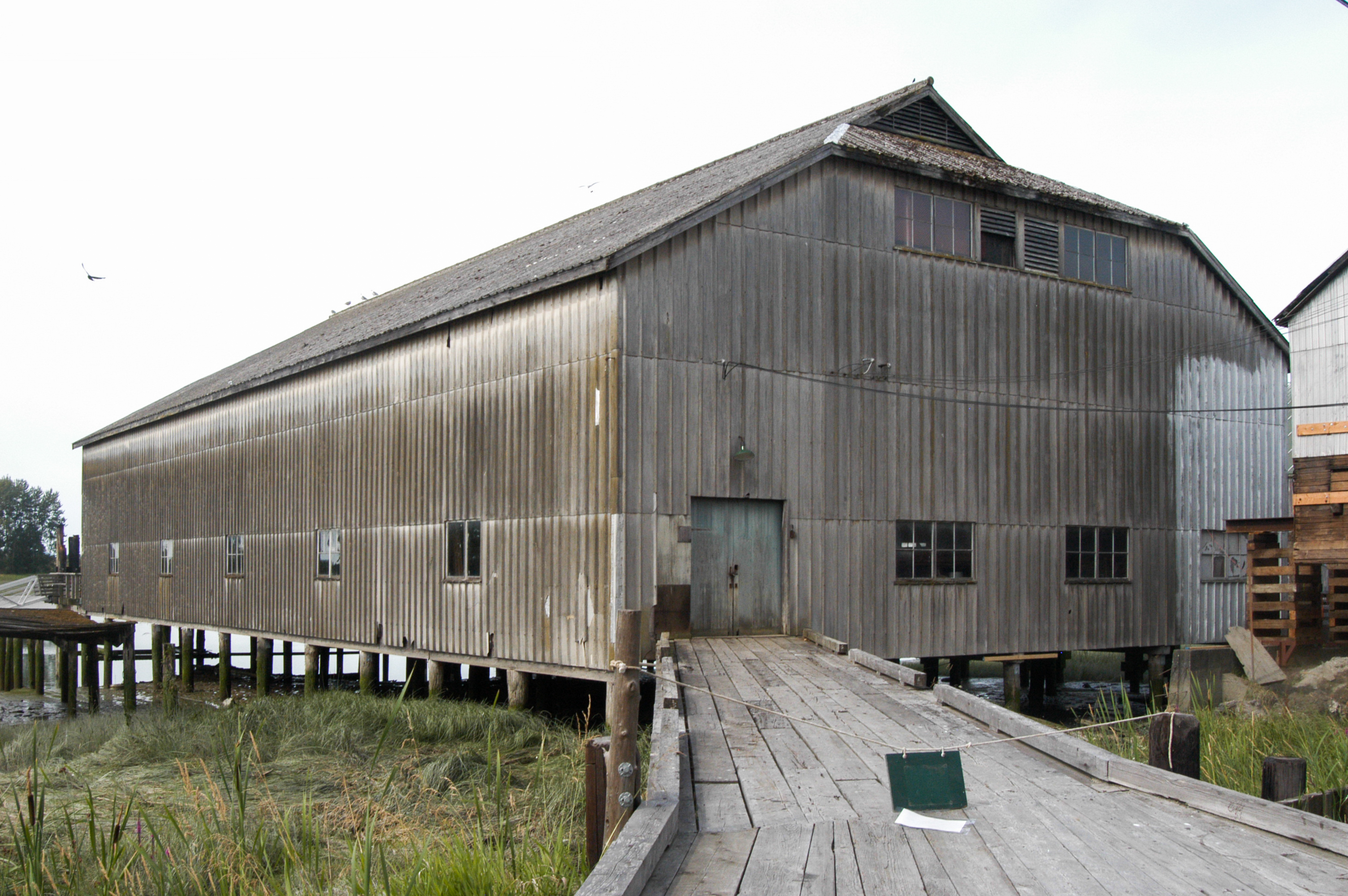 Britannia Shipyards 全景，Fraser River 岸边排列的桩基木建筑群，栈道连接各栋