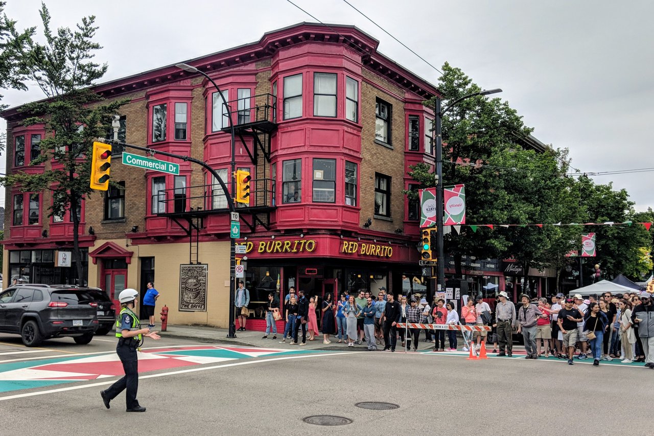 2019 年 Italian Days festival 期间 East 1st Avenue 与 Commercial Drive 路口，人群占据街角，街面标识把 Little Italy 的身份临时铺满路口