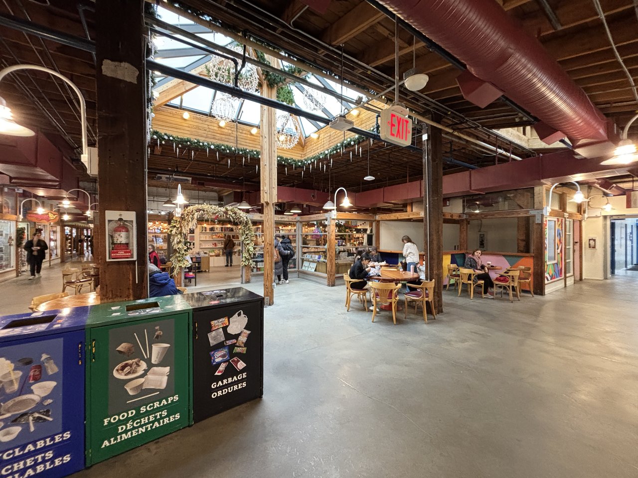 Net Loft 内部保留的暴露木柱和钢桁架结构，原工业仓库改造为集市空间，桁架承重系统在商业功能中保留可见