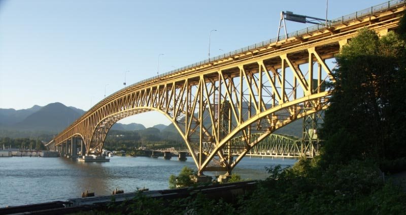 Ironworkers Memorial Bridge 当代桥体、Highway 1 六车道与 Burrard Inlet 及北岸山地背景