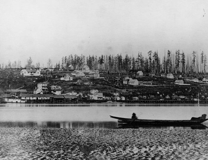 1865 年从 Fraser River 看 New Westminster 早期聚落，河道宽阔，北岸高地可见稀疏建筑