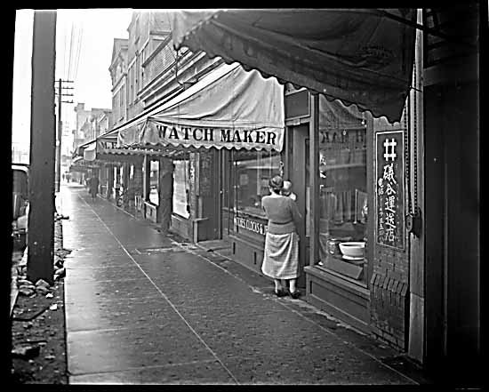 1928 年 Powell Street 商业街景，日文招牌和商铺沿街排列，前景是一家钟表店