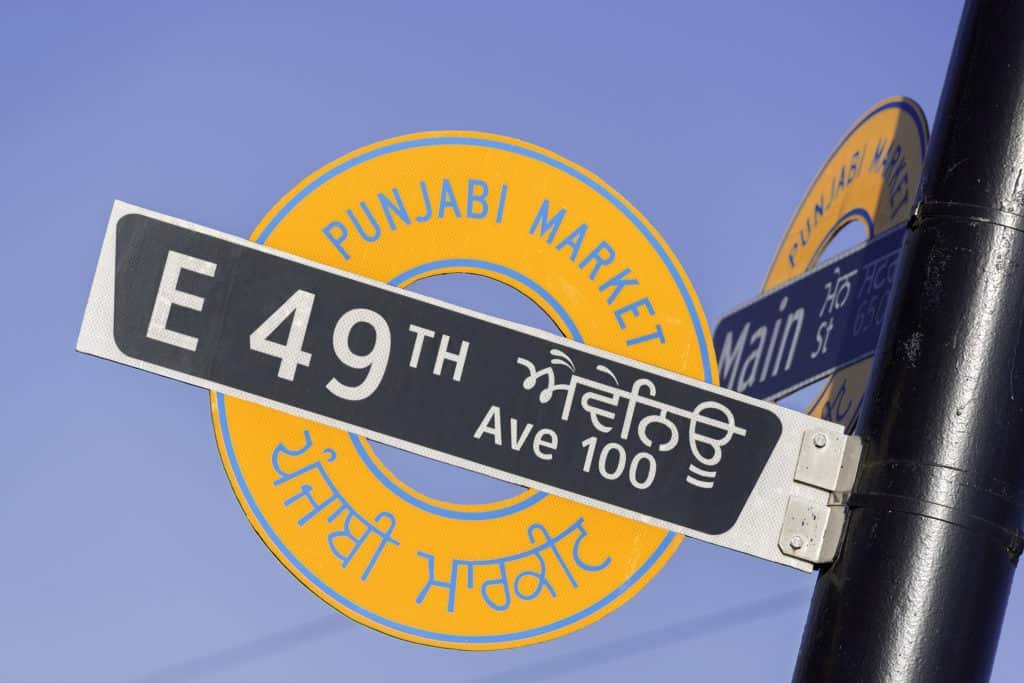 Main Street 两侧小开间独立店面，展示 Punjabi Market 沿街商业的原始尺度