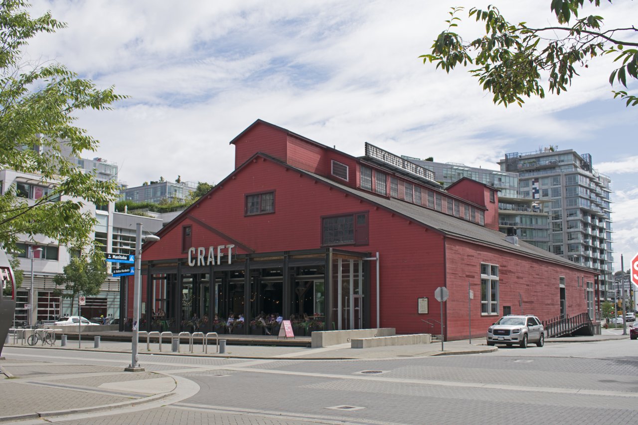 Salt Building 外观：红色木板外墙、锯齿形屋顶的工业仓库，与周围奥运村住宅形成材质对比