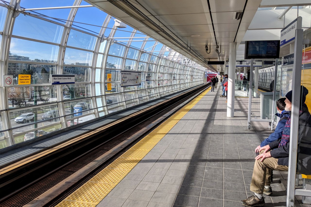 Main Street-Science World 站台层，高架导轨从站台两侧延伸，远处可见 Science World 穹顶
