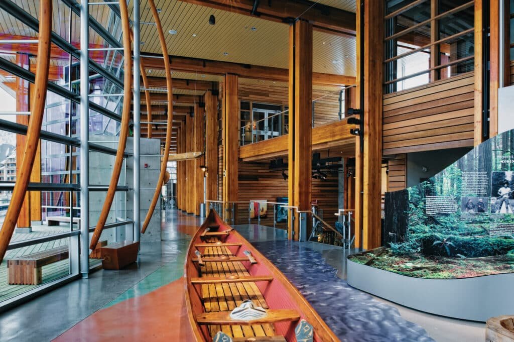 SLCC Great Hall 内的 canoe 与 glulam 成对木柱，canoe 悬吊在 post-and-beam 框架下