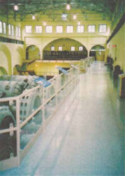 Stave Falls Powerhouse 内部机组大厅，水平轴涡轮机和发电机排列整齐，上层参观通道俯瞰整个大厅，屋顶行车吊轨道可见