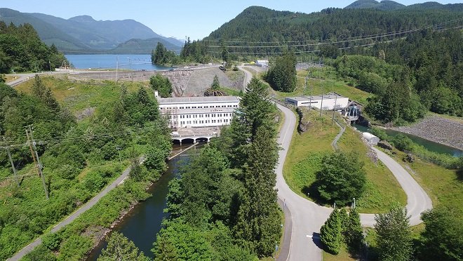 Stave Falls Powerhouse 老厂房外观，钢筋混凝土矩形体量，左右对称多格工业窗，屋顶台阶式压顶，建筑坐落在峡谷边缘