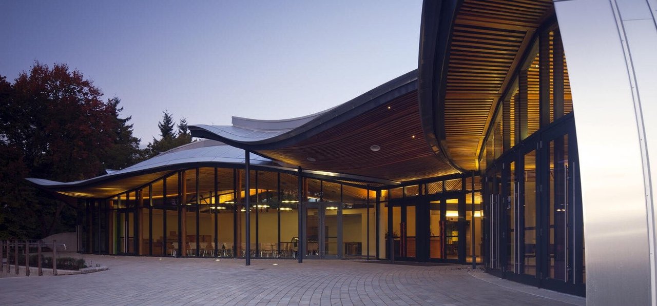 VanDusen Visitor Centre 胶合木屋顶结构，弯曲胶合木梁从中心向外辐射排列，CNC 切割的梁端连接节点清晰可见