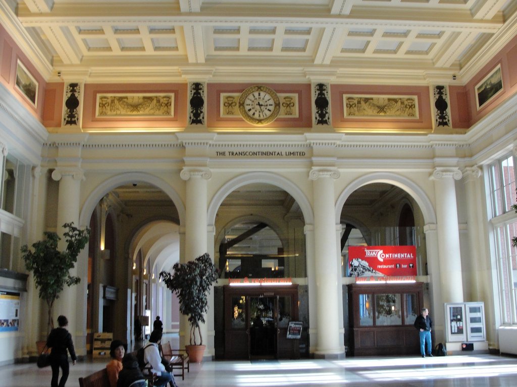 Waterfront Station 大厅内景，Ionic 内柱沿周界排列，柱顶上方可见壁画，东西墙高处有相向大钟