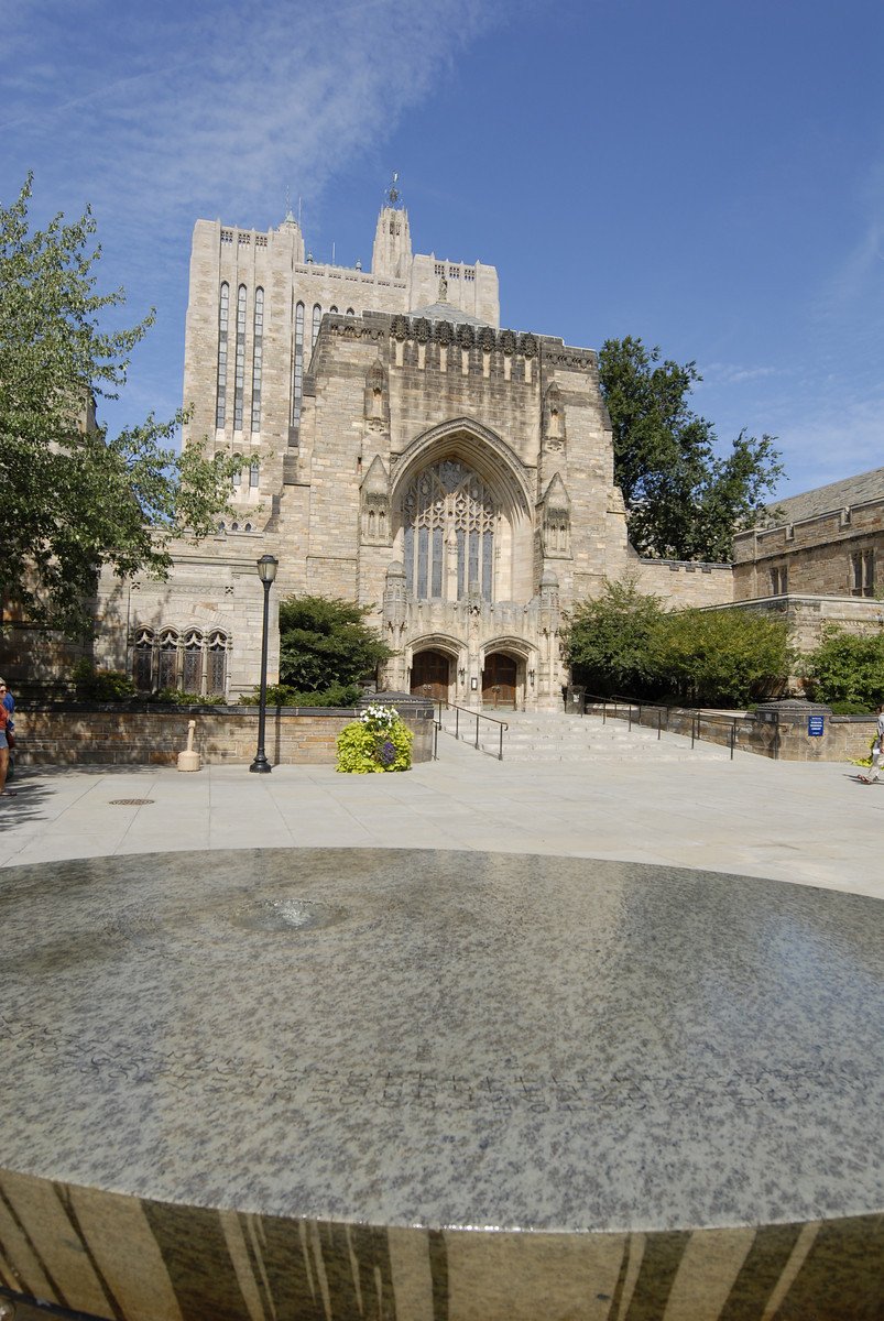 The Women's Table at Rose Walk, an elliptical black stone table with a thin water layer covering spiral numbers, Sterling Memorial Library in the background