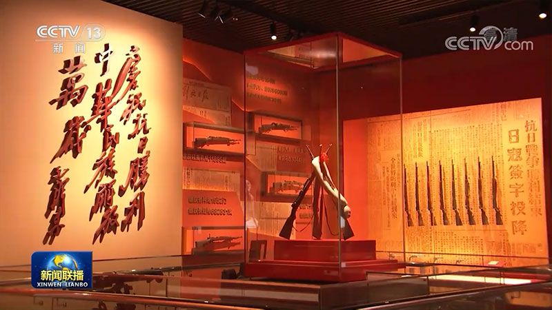 展厅内陈列的革命文物展柜,步枪与旗帜陈列在红色背景中