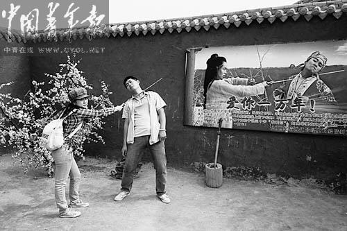 Three young people are standing in front of a large poster depicting a historica