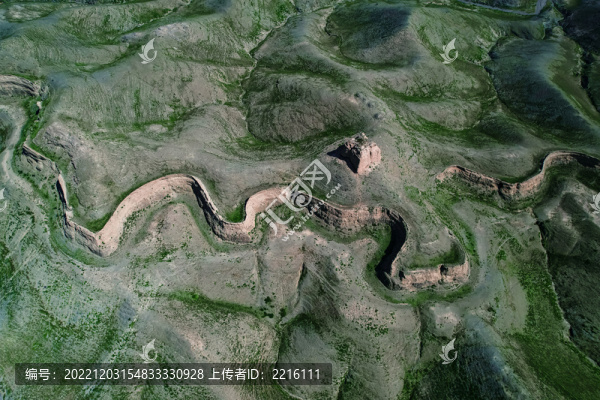 A winding section of the Great Wall of China runs through green, hilly terrain n