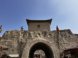 A fortified structure featuring a traditional tangtu wall with a large archway i
