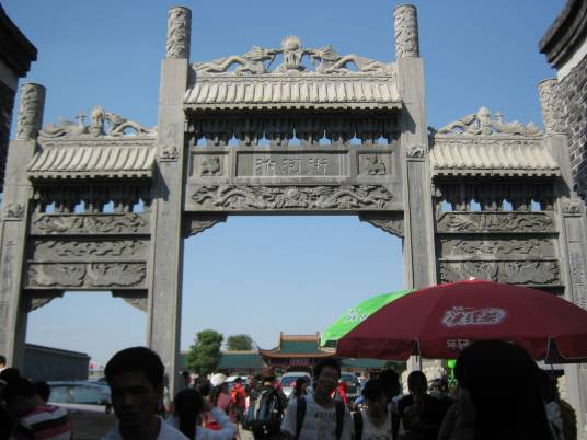 汴河街南入口仿古牌坊，灰瓦翘角，匾额上书"汴河街"三字，后方是街内店铺的灰瓦白墙立面