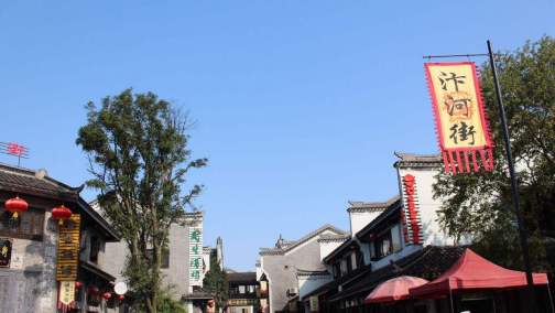 汴河街内部，两侧仿古店铺一字排开，灰瓦翘檐、朱红门窗、统一招牌，路面为现代石板铺装