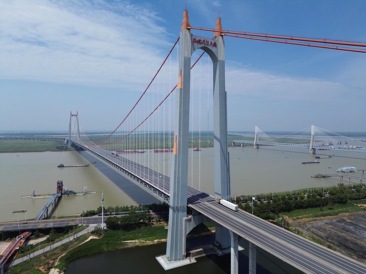 杭瑞高速洞庭湖大桥全景，两座H形索塔矗立洞庭湖面，红色悬索拉起钢桁梁桥面