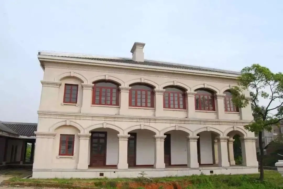 岳州关正面全景，白墙灰瓦红窗的两层券廊西式建筑，坐落在城陵矶港区山丘上
