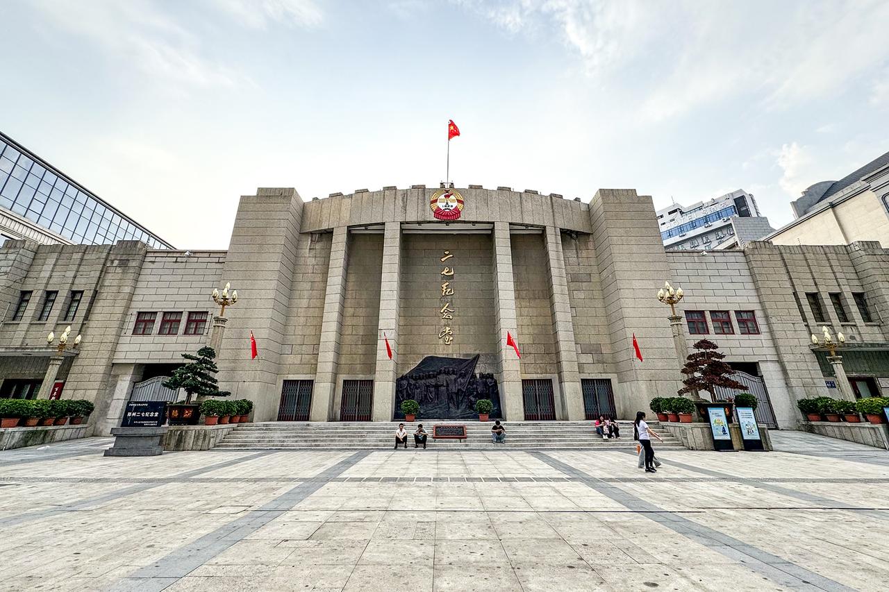 二七纪念堂正面外观，青砖墙面、红瓦尖顶，正门上方可见堂徽与铸铁浮雕