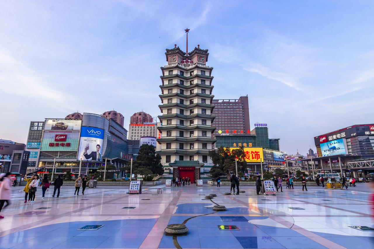 二七广场夜景，塔身暖黄灯光与周边商业LED灯光在同一视野中的对比