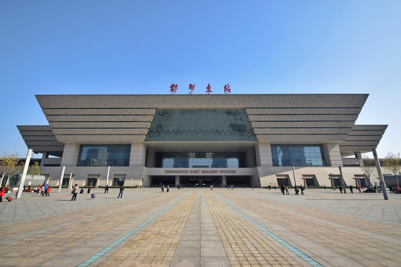 郑州东站正面全景，建筑立面棱角分明呈方鼎造型，站前广场开阔