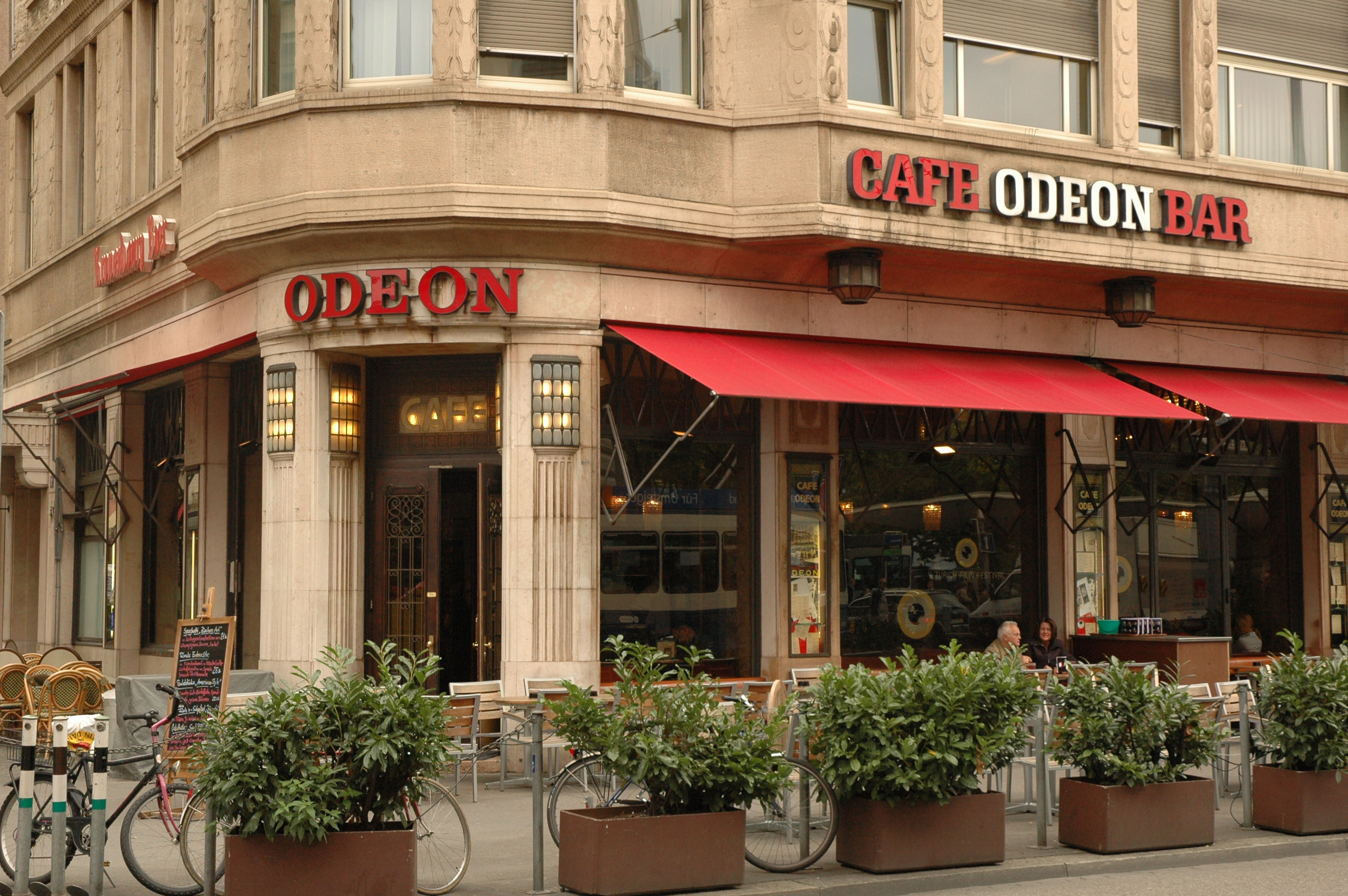 Café Bar Odeon 外立面正面，可见大窗户与露天座位