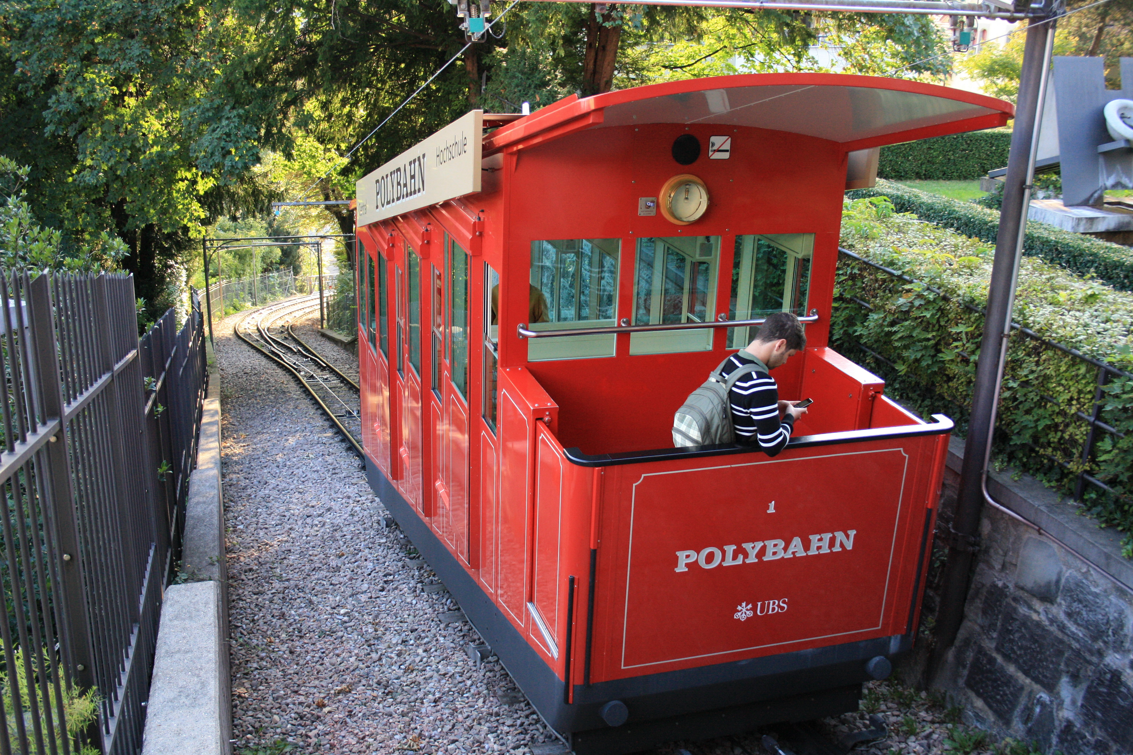 Polybahn 红色车厢在坡道上行驶，背景可见苏黎世城市建筑